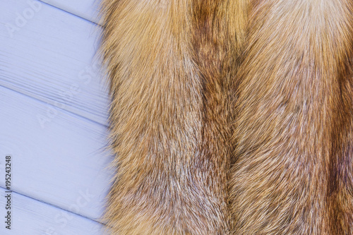 Red fox skin on a gray wooden background. Beautiful fur of a red fox