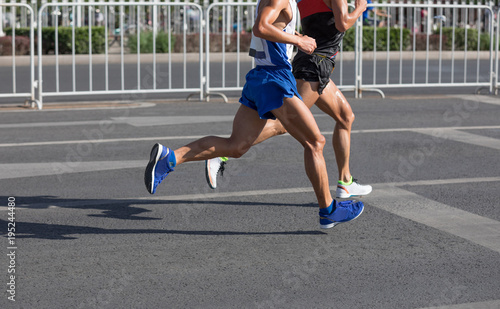 Legs of marathon runners running on city road