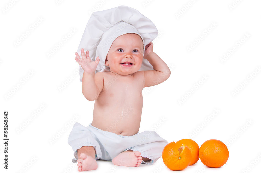 A small child eats an orange slice in a chef suit on a white background. A small child eats an orange slice in a chef suit on a white background.