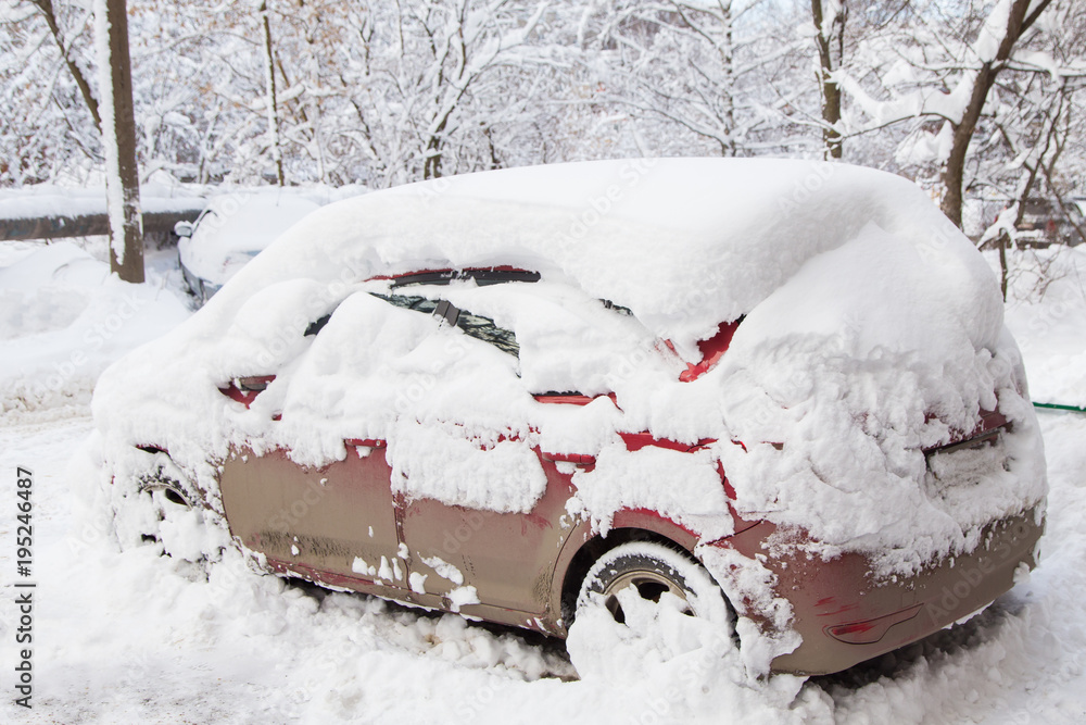 Red car under snow in snowbank after blizzard	
