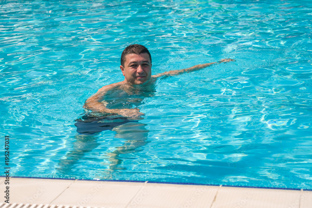Portrait of young man relaxing in swimming pool, summer outdoor concept