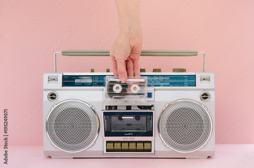 Hand inserting music tape into retro tape deck