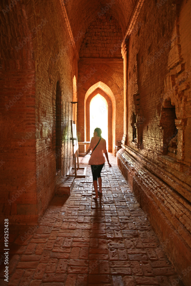 Lady walks through the orange interior of a temple in Bagan, Myanmar