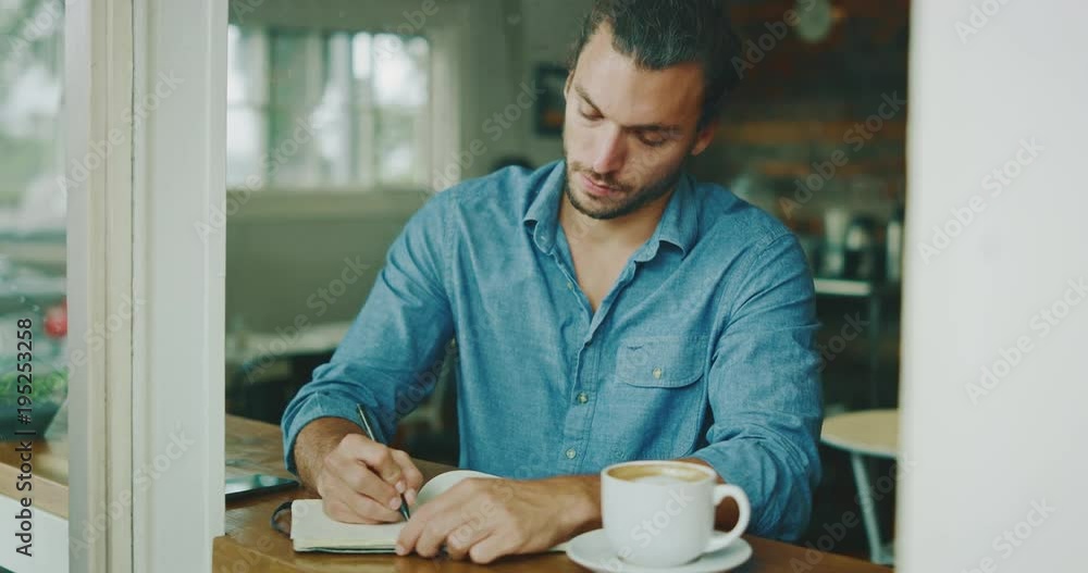 Young man writing in notebook in coffee shop Young man writing in notebook in coffee shop