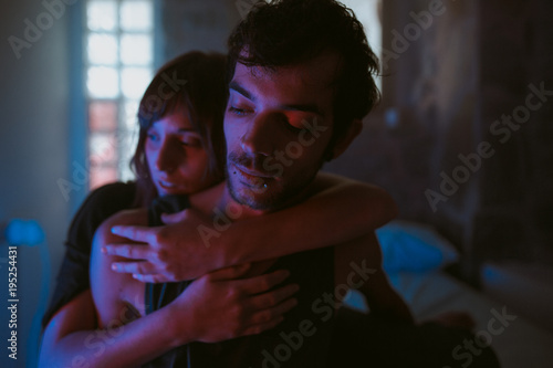 young couple hugging in a blue iluminated bedroom photo