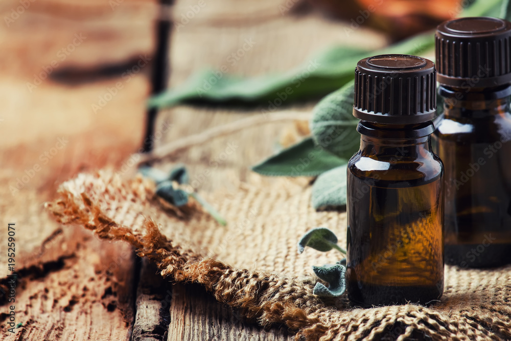 Essential sage oil in brown bottle on the vintage wooden blackground, rustic style, selective focus Essential sage oil in brown bottle on the vintage wooden blackground, rustic style, selective focus