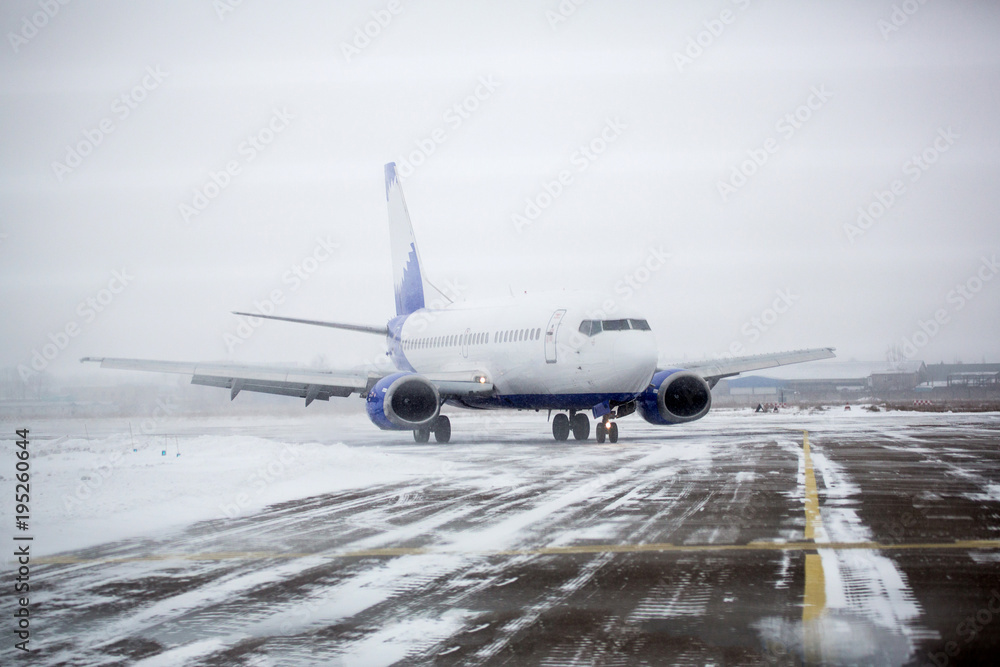 Airliner on runway in blizzard. Aircraft during taxiing at heavy snow. Passenger plane in snow at airport. Modern twin-engine passenger airplane taxiing for take off at airport during snow blizzard Airliner on runway in blizzard. Aircraft during taxiing at heavy snow. Passenger plane in snow at airport. Modern twin-engine passenger airplane taxiing for take off at airport during snow blizzard
