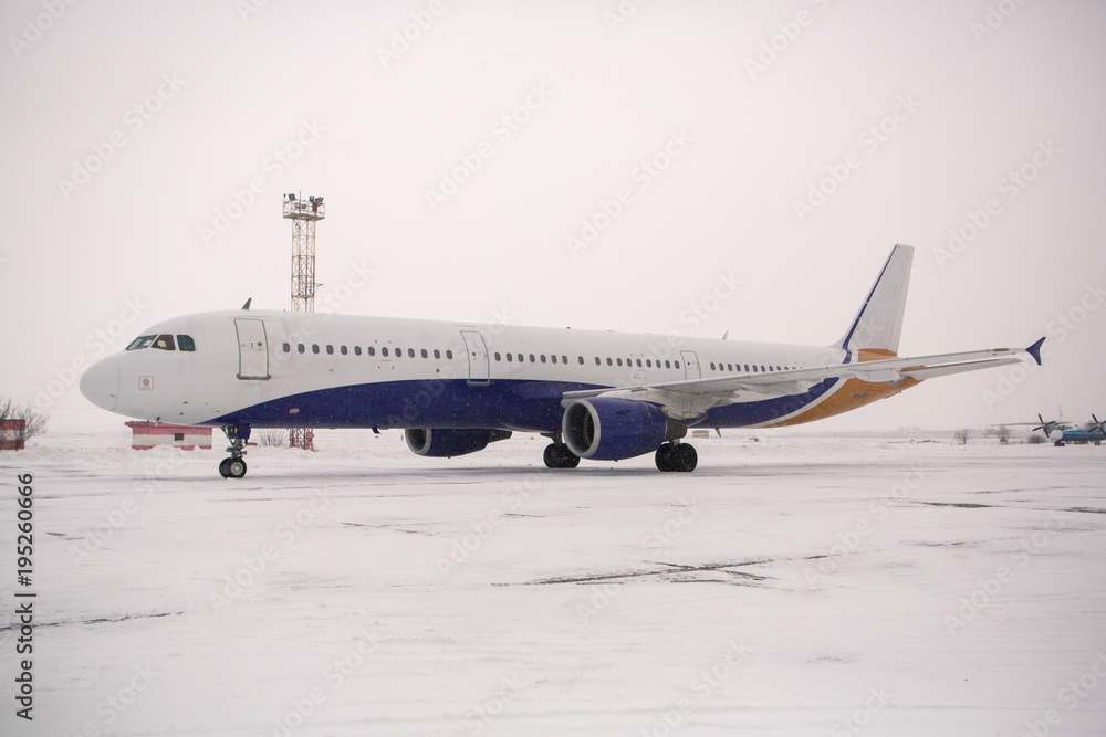 Airliner on runway in blizzard. Aircraft during taxiing at heavy snow. Passenger plane in snow at airport. Modern twin-engine passenger airplane taxiing for take off at airport during snow blizzard