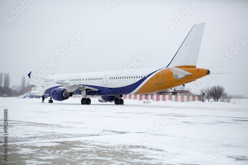 Fototapeta Naklejka Na Ścianę i Meble -  Airliner on runway in blizzard. Aircraft during taxiing at heavy snow. Passenger plane in snow at airport. Modern twin-engine passenger airplane taxiing for take off at airport during snow blizzard