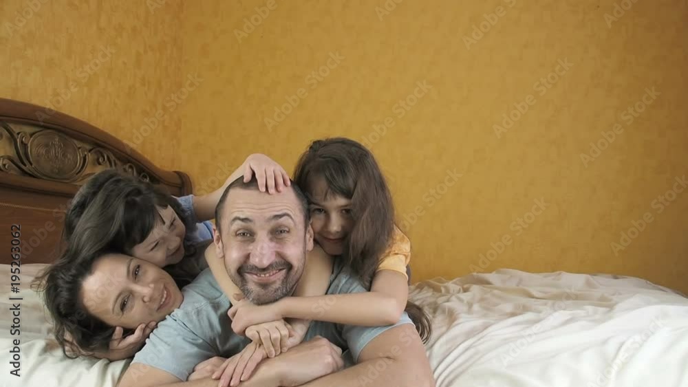 A happy family in the bedroom. A child wakes up parents. Parents with children lie on the bed. A happy family in the bedroom. A child wakes up parents. Parents with children lie on the bed.