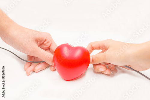 Fototapeta Naklejka Na Ścianę i Meble -  Hands with charging cables to help recovering heart on white background. Heart disease protection, proactive checkup, diagnosis, sickness prevention, healthcare examination tool concept.