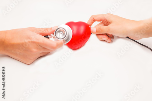 Hands with stethoscope and charging cable to check and cure heart on white background. Heart disease protection, proactive checkup, diagnosis, sickness prevention, healthcare examination tool concept.