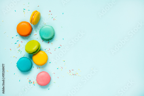 Colorful macaroons and sugar sprinkles arranged over blue background. Copy space.