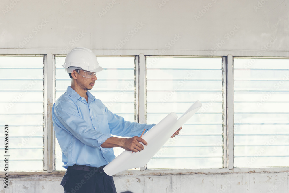 Success Engineer wear white helmet for safety and checking building plans blue print. construction Concept. Success Engineer wear white helmet for safety and checking building plans blue print. construction Concept.