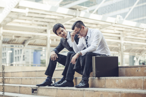 young businessman touching his forehead while his colleague consoling him