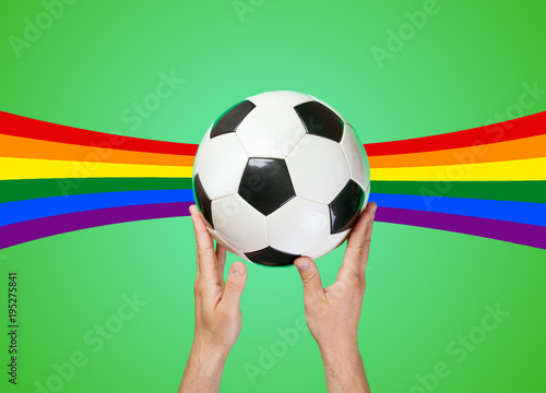 Hand holding football ball on green background