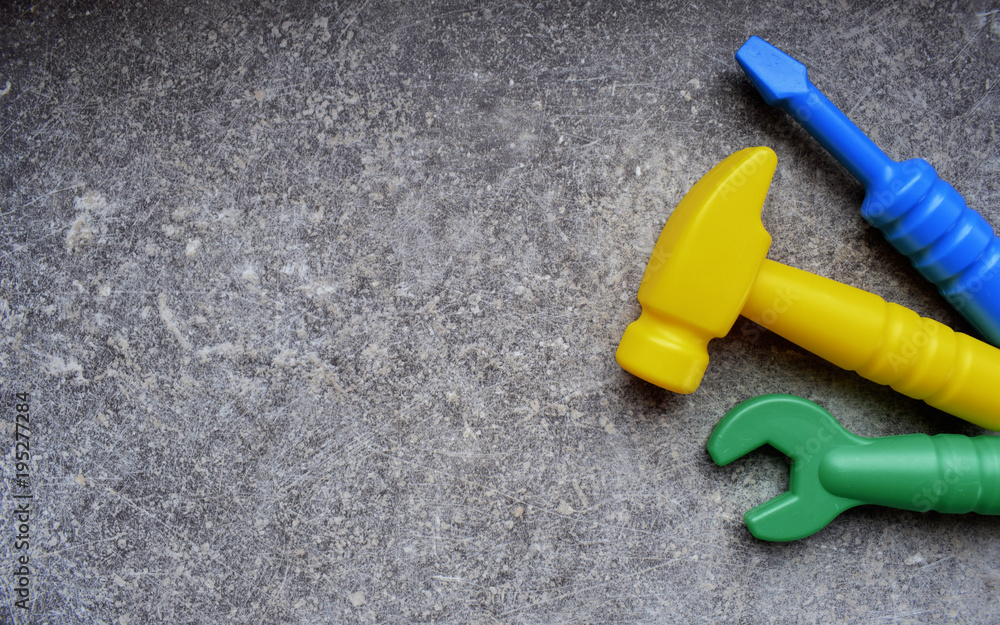 Toys background. Kids toys top view. Toy tools on grey grunge background. Three kids tools on grey table. Background with space for text. Toys background. Kids toys top view. Toy tools on grey grunge background. Three kids tools on grey table. Background with space for text.