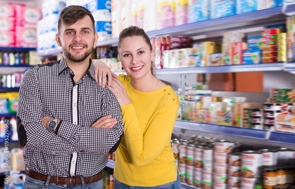 Couple standing among shelves with groceries