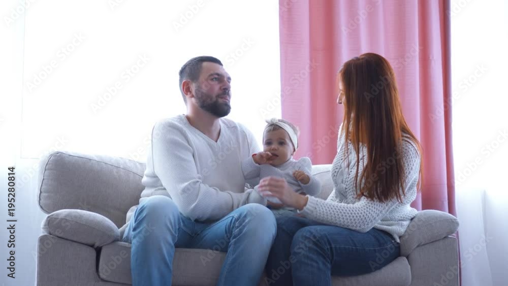 Happy mother and father playing with small girl on sofa Happy mother and father playing with small girl on sofa