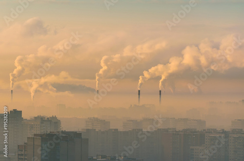 Urban landscape smoked polluted atmosphere from emissions of plants and factories  view of pipes with smoke and residential apartment buildings.