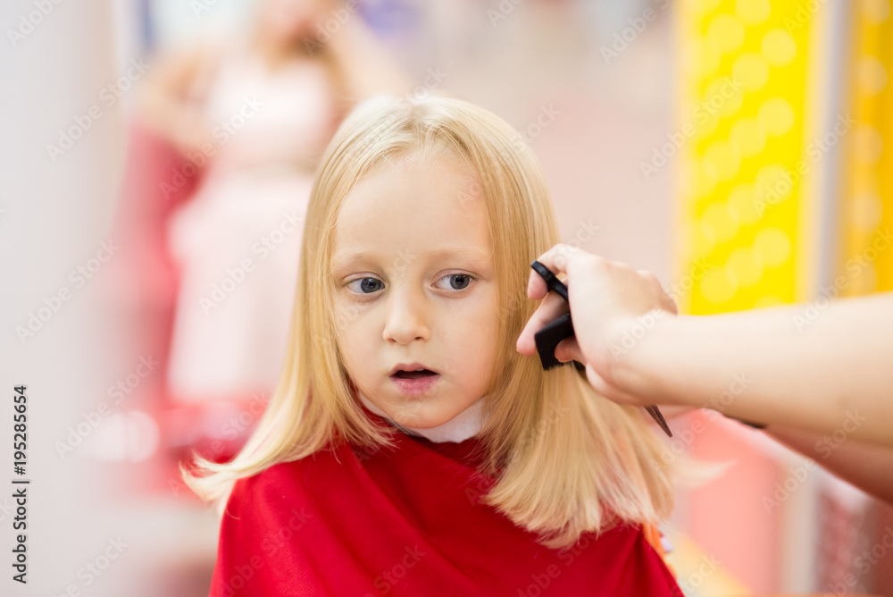 little girl smiles and does a haircut in a beauty salon. Stock Photo ...