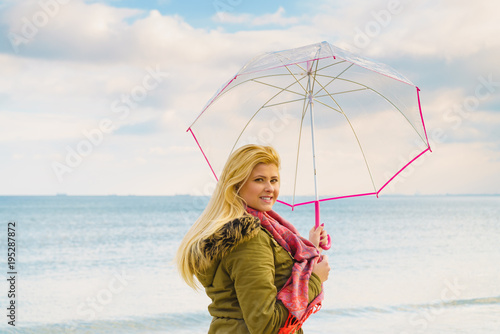 Woman standing with transparent umbrella on beach