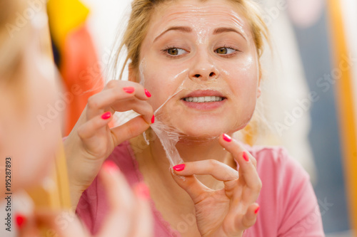 Woman peeling off gel mask from face