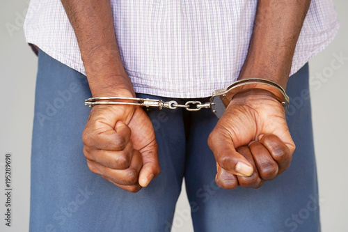 Close-up. Arrested man handcuffed hands at the back. Prisoner or arrested terrorist, close-up of hands in handcuffs, selective focus.