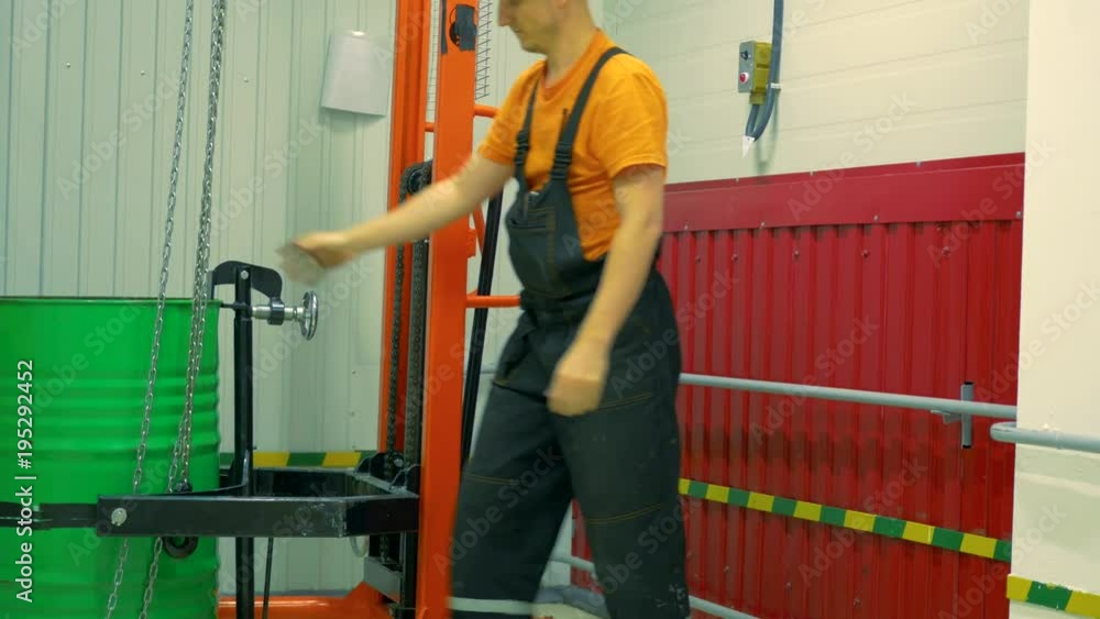 The worker lowers the barrel using a lifting mechanism. The worker lowers the barrel using a lifting mechanism.