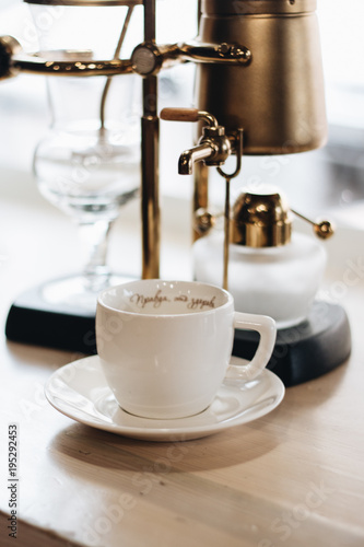 Cup of delicious coffee and retro style coffee machine, closeup