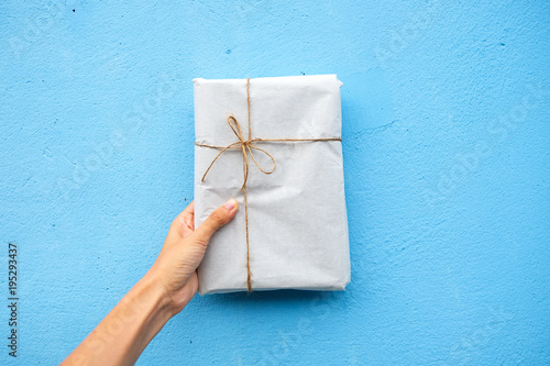 Female hand holding gift box with blue background