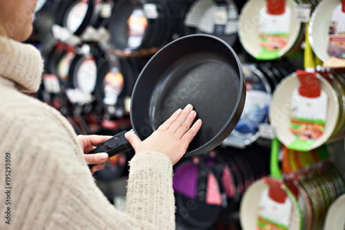 Woman chooses frying pan in crockery store
