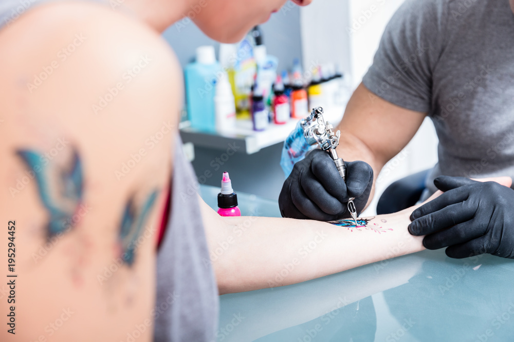 Close-up of the hands of a skilled tattoo artist wearing black gloves while setting a sterile machine for tattooing in a modern studio Close-up of the hands of a skilled tattoo artist wearing black gloves while setting a sterile machine for tattooing in a modern studio