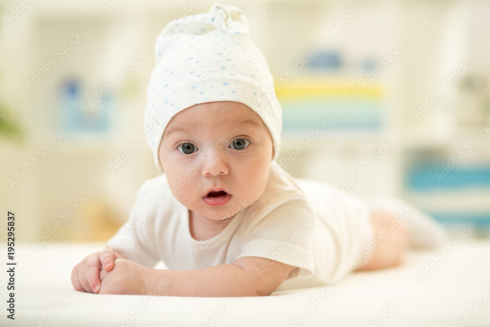 Baby lying on soft bed cover with cap Baby lying on soft bed cover with cap