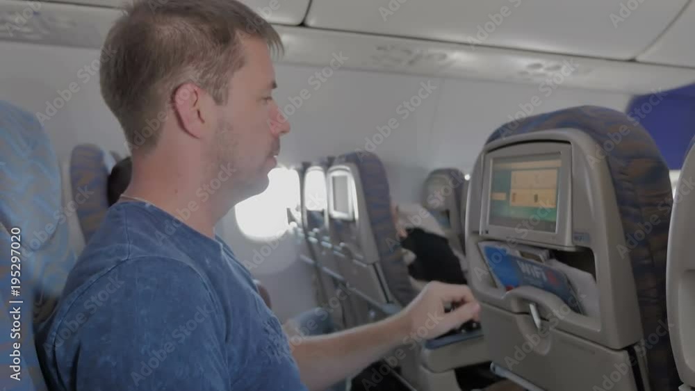 The man clicks on the touch screen in the plane. The man clicks on the touch screen in the plane.