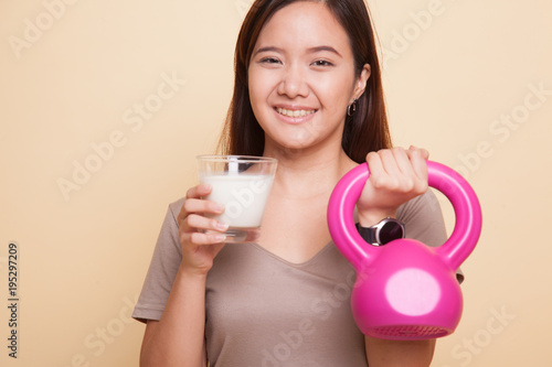 Healthy Asian woman drinking a glass of milk and kettlebell