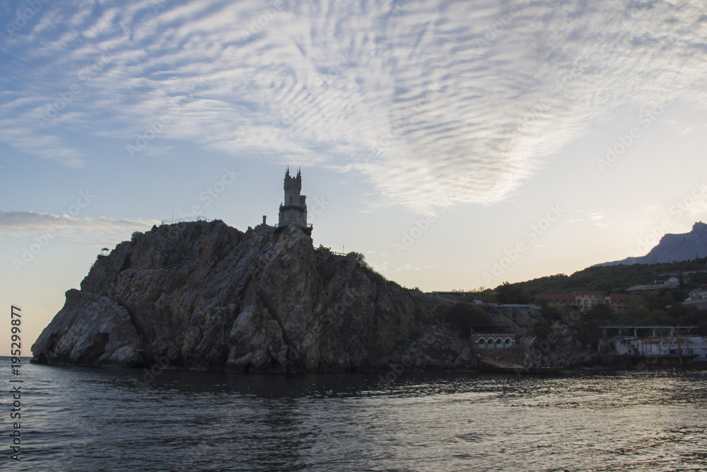 A tower on a rocky seashore in the light of the setting sun
