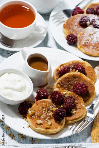 sweet corn pancakes with berries and caramel sauce on white table, top view