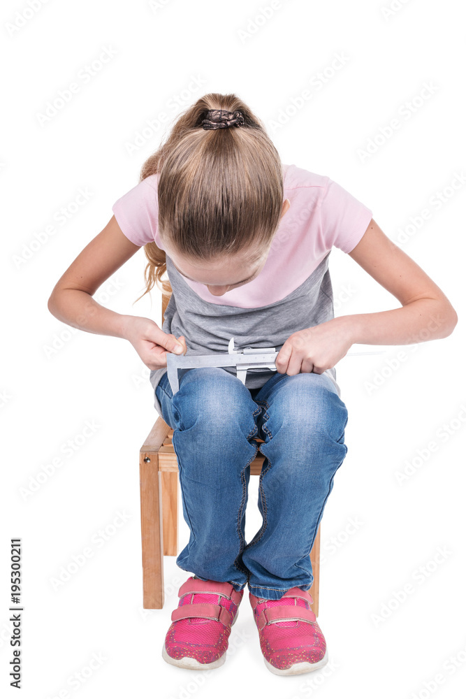Young girl sitting on a chair, measures the thickness of her legs with a calipers, isolated on a white background