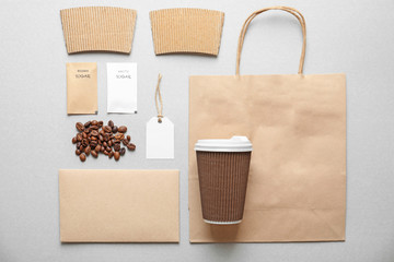 Composition with blank cup, paper bag and sugar packages as mockups for branding on grey background