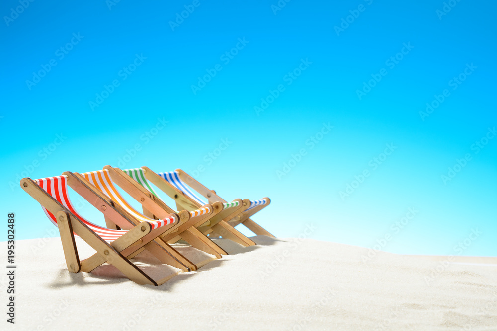 Multi-colored lounge chairs in a row on the sandy beach. Multi-colored lounge chairs in a row on the sandy beach.