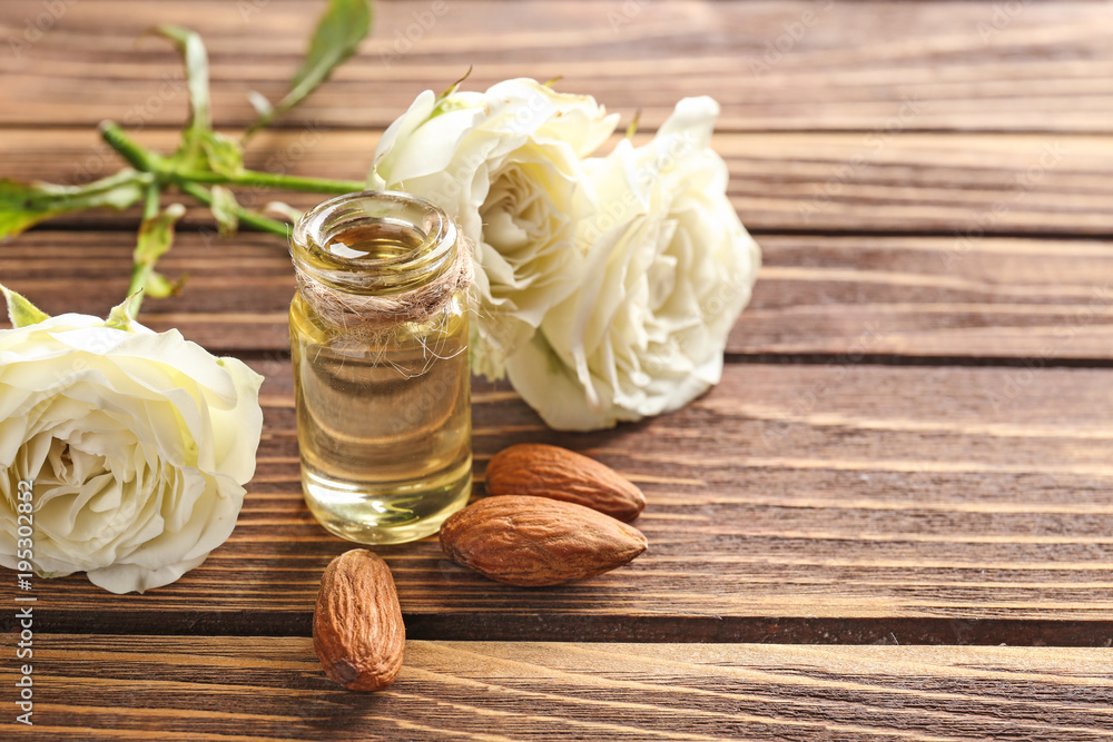 Bottle of perfume oil, almond and roses on table Bottle of perfume oil, almond and roses on table