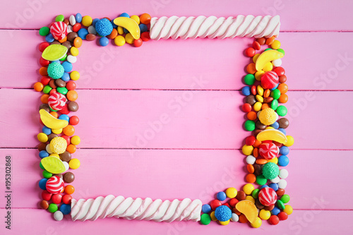 Frame of colorful candies on wooden background  flat lay