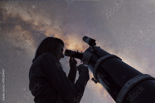 Silhouette of a girl and telescope with de-focused Milky Way stars. 