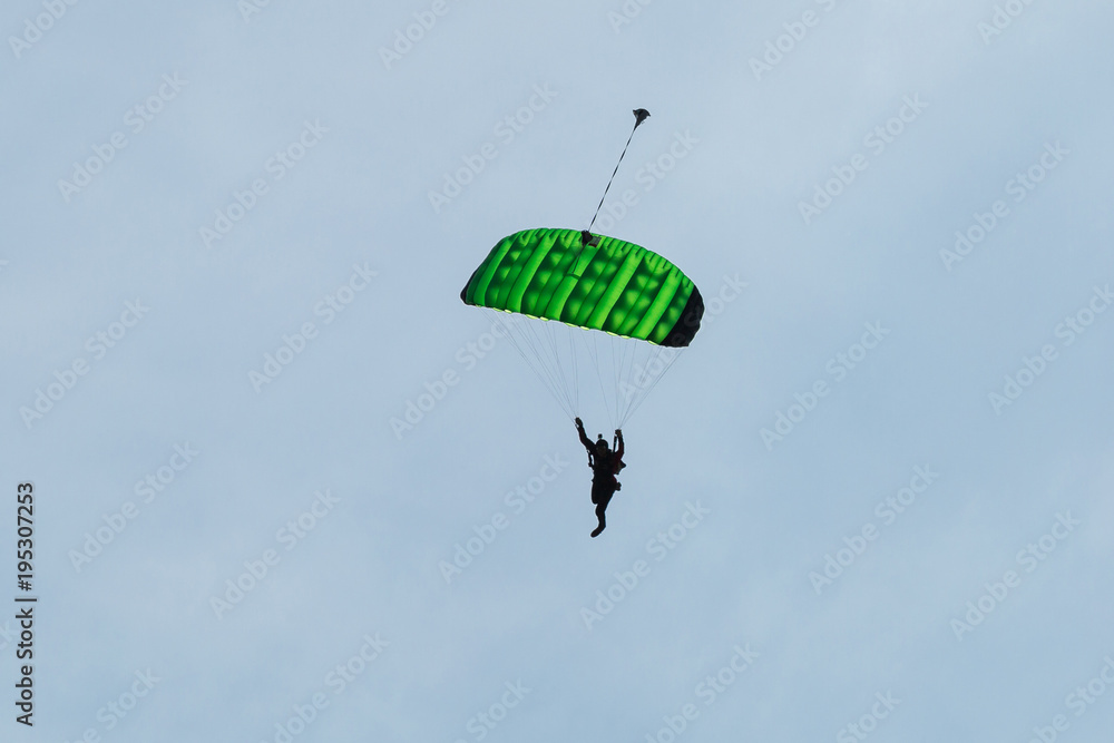 Parachutist with Green Parachute against Clear Blue Sky Parachutist with Green Parachute against Clear Blue Sky