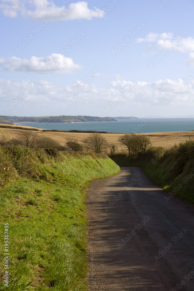 UK, Wales, Pembrokeshire, empty country road winding down towards coast UK, Wales, Pembrokeshire, empty country road winding down towards coast