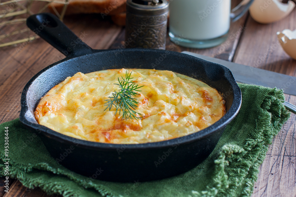 Potato casserole in a cast-iron frying pan on a wooden table, horizontal