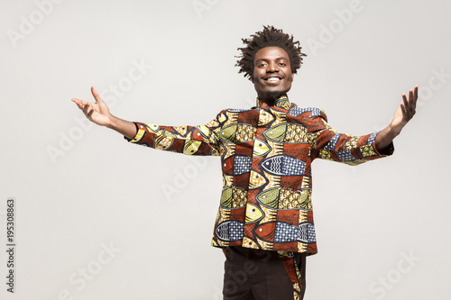 Friendly afro man in traditional clothes toothy smile, say welcome
