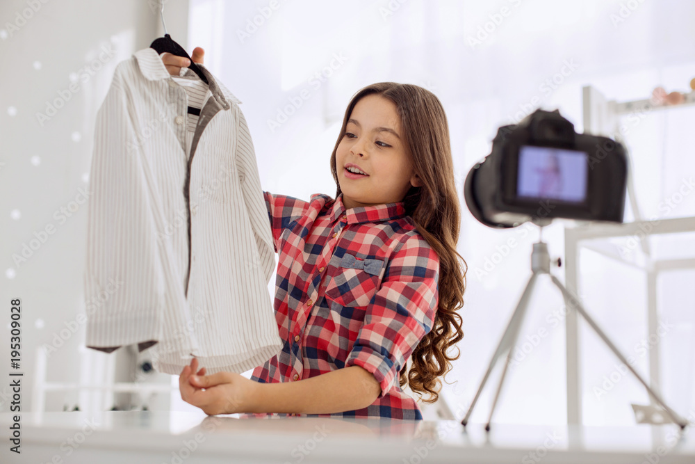 Good purchase. Pretty upbeat pre-teen girl showing a shirt to the camera and telling about her shopping day while filming a video blog Good purchase. Pretty upbeat pre-teen girl showing a shirt to the camera and telling about her shopping day while filming a video blog