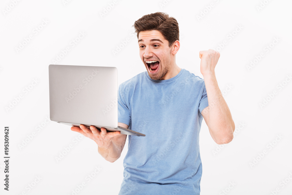 Happy successful man in t-shirt clenching fist like lucky guy or winner while working in internet on laptop, isolated over white background Happy successful man in t-shirt clenching fist like lucky guy or winner while working in internet on laptop, isolated over white background